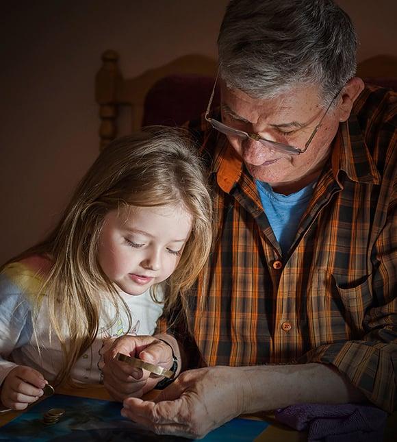 David showing a gold coin to his granddaughter at the kitchen table